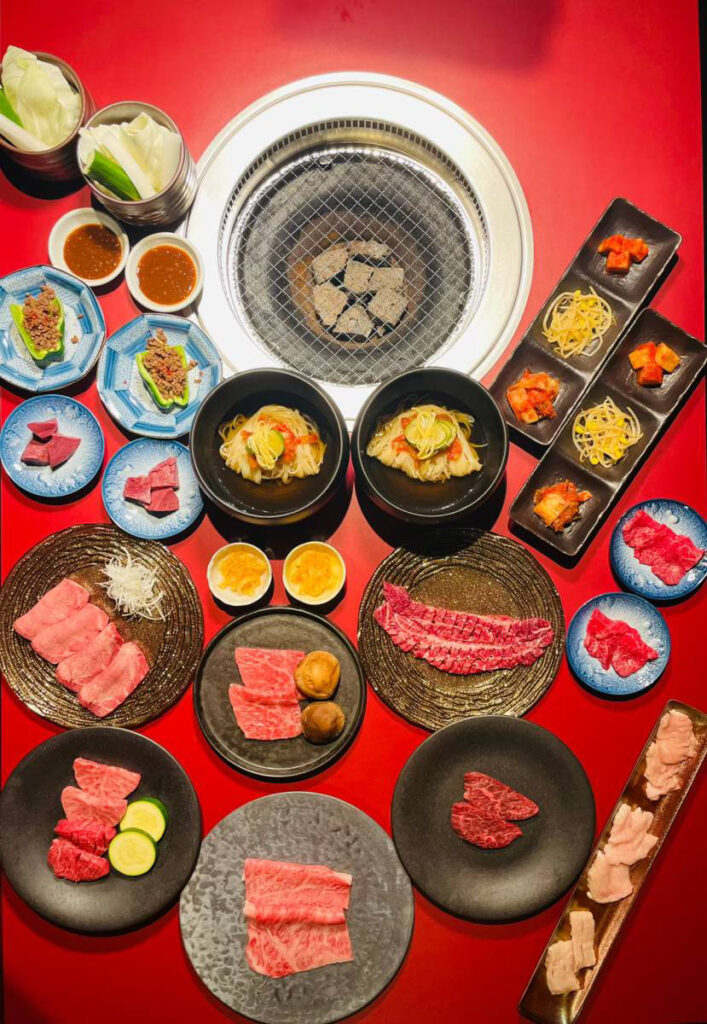 赤いテーブルに並んだ峯がみコースの肉と前菜